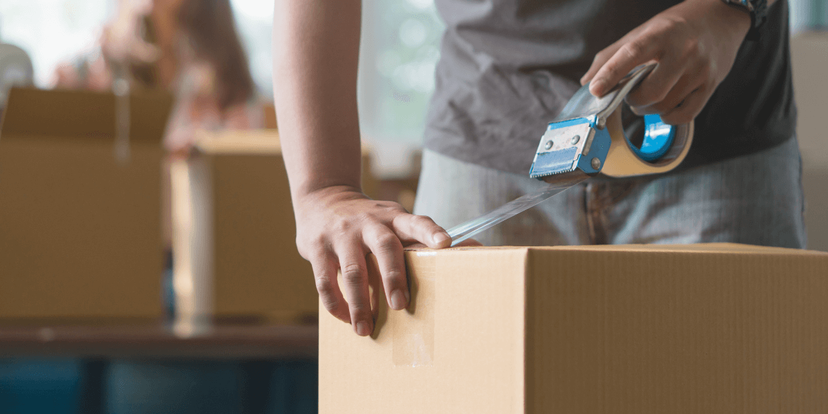 person taping a moving box
