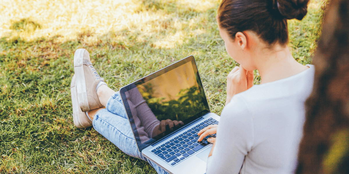 woman using laptop on the grass