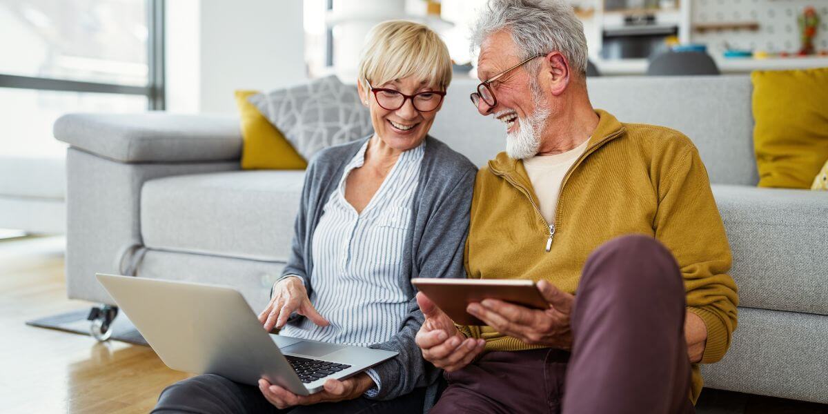 senior internet plans couple sits on floor with devices