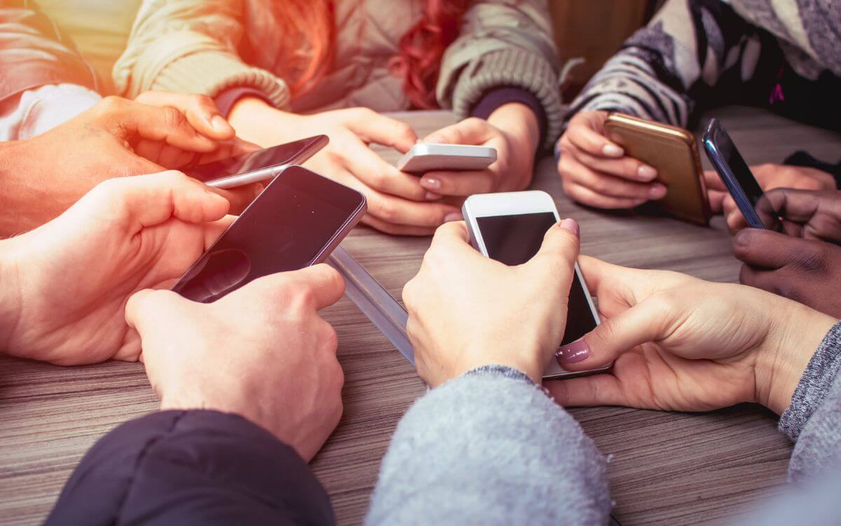 group of hands holding smartphones at table