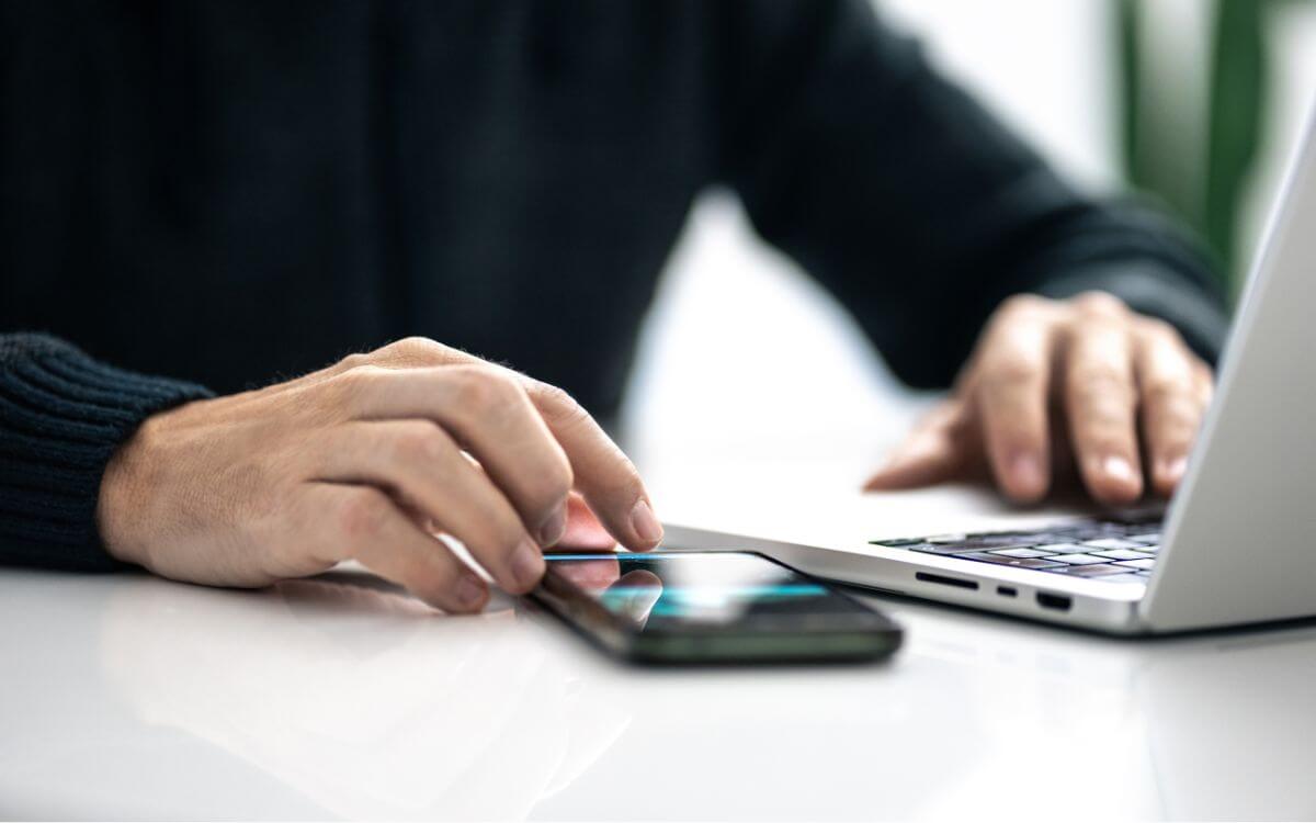 person at desk with phone and laptop