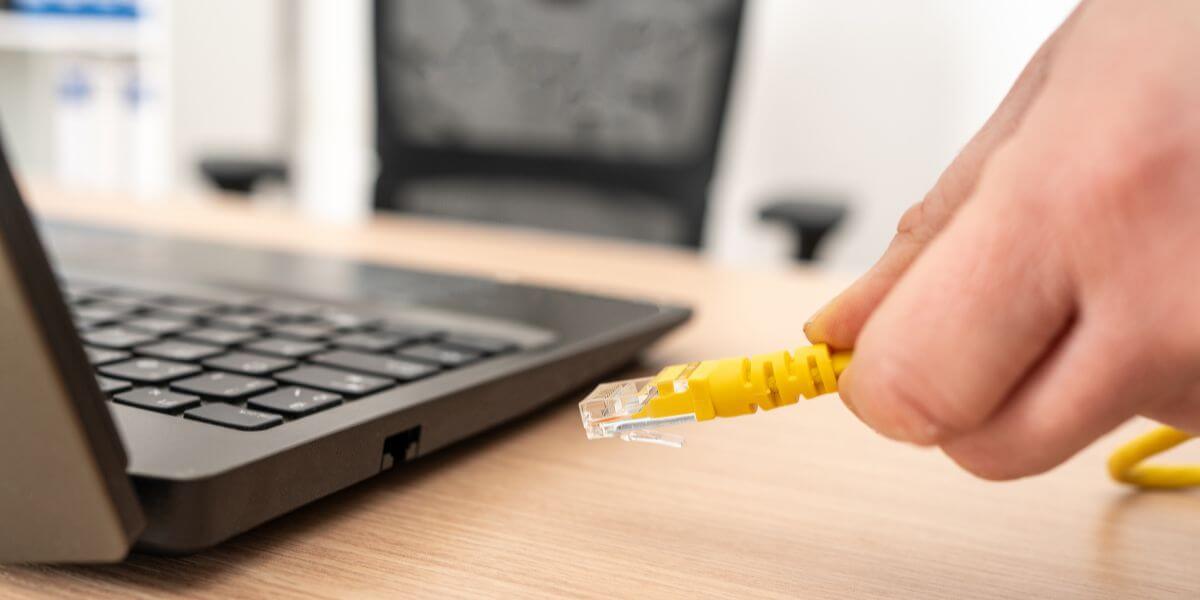 hand plugging in ethernet cable to laptop