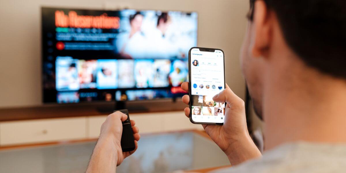 man holding phone watching tv