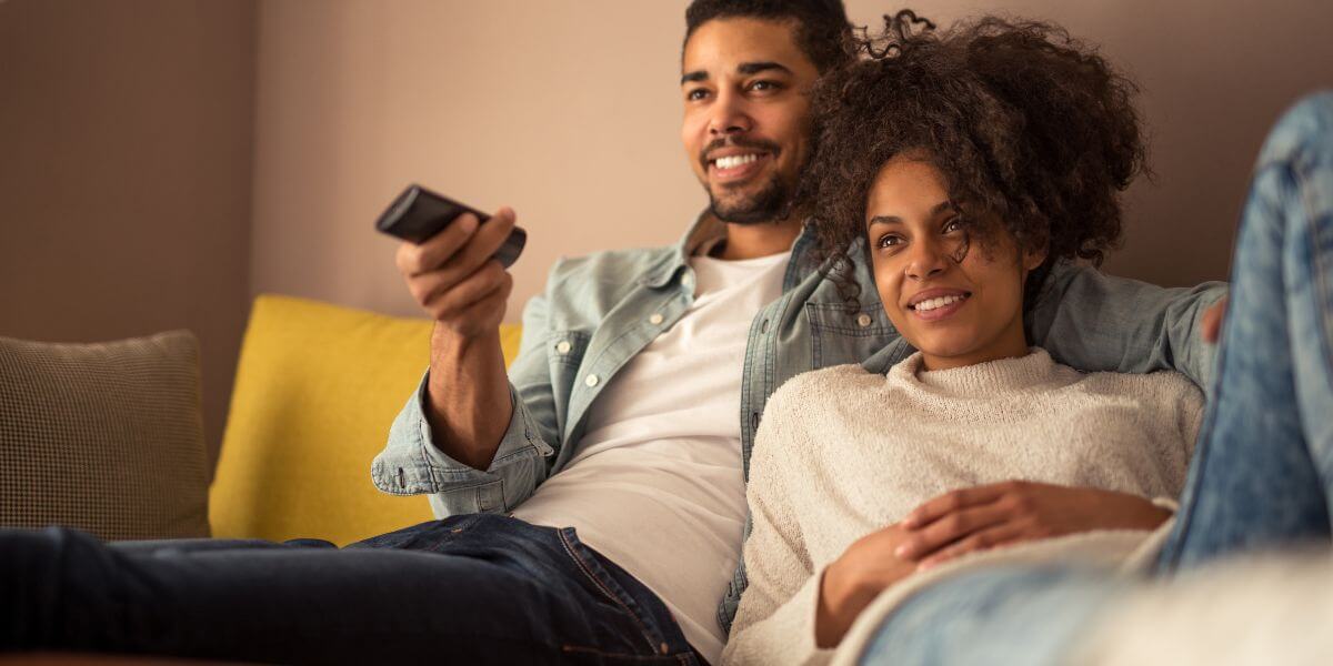 couple sitting on couch with remote