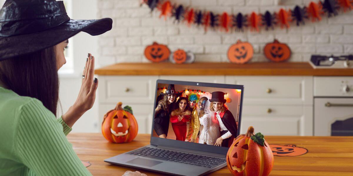 woman waving at laptop with halloween decorations