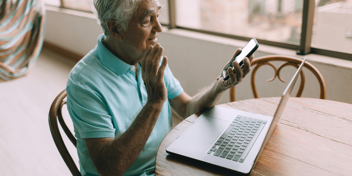 older gentleman using his phone and laptop