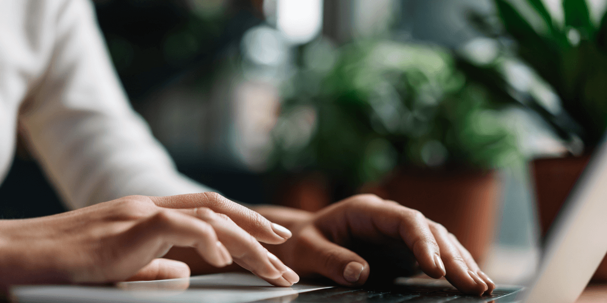 person's hands typing on a laptop