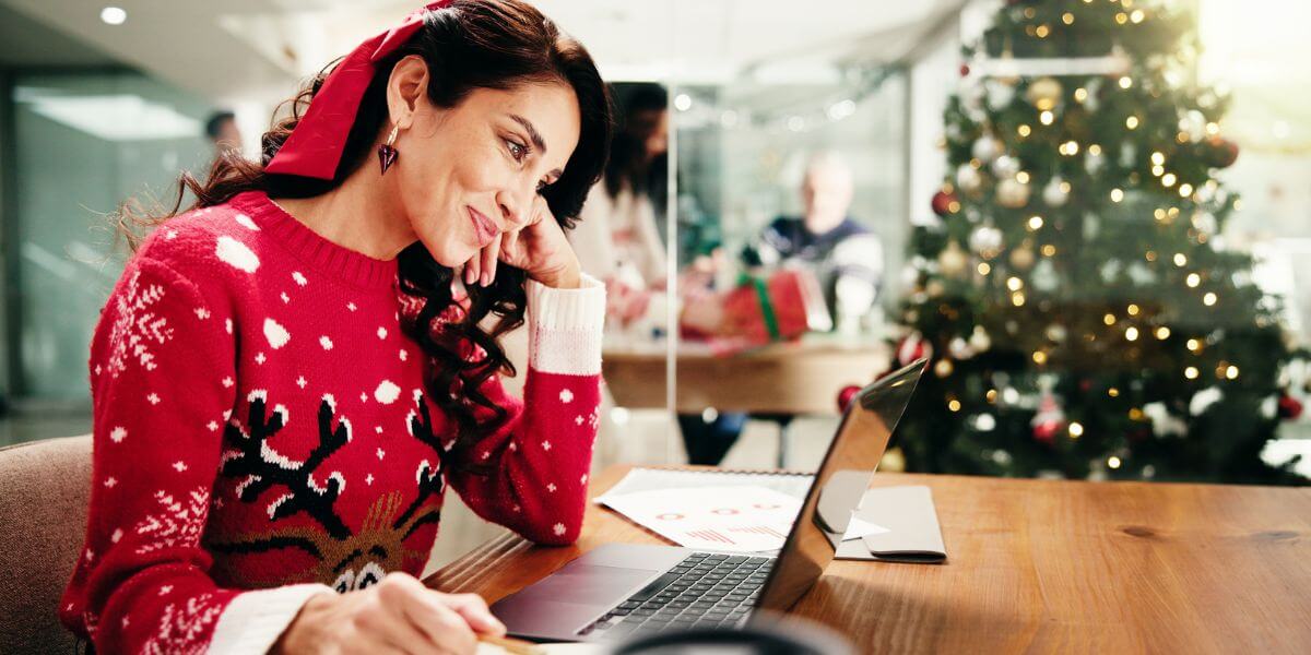 woman in holiday sweater using laptop