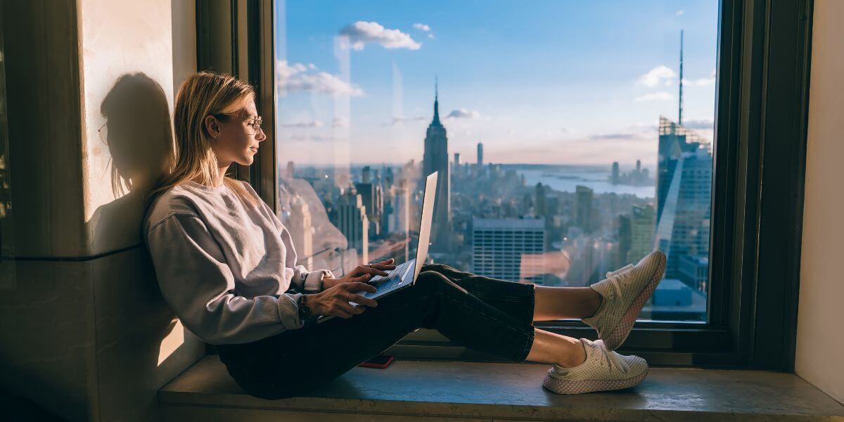 woman working by window overlooking NYC