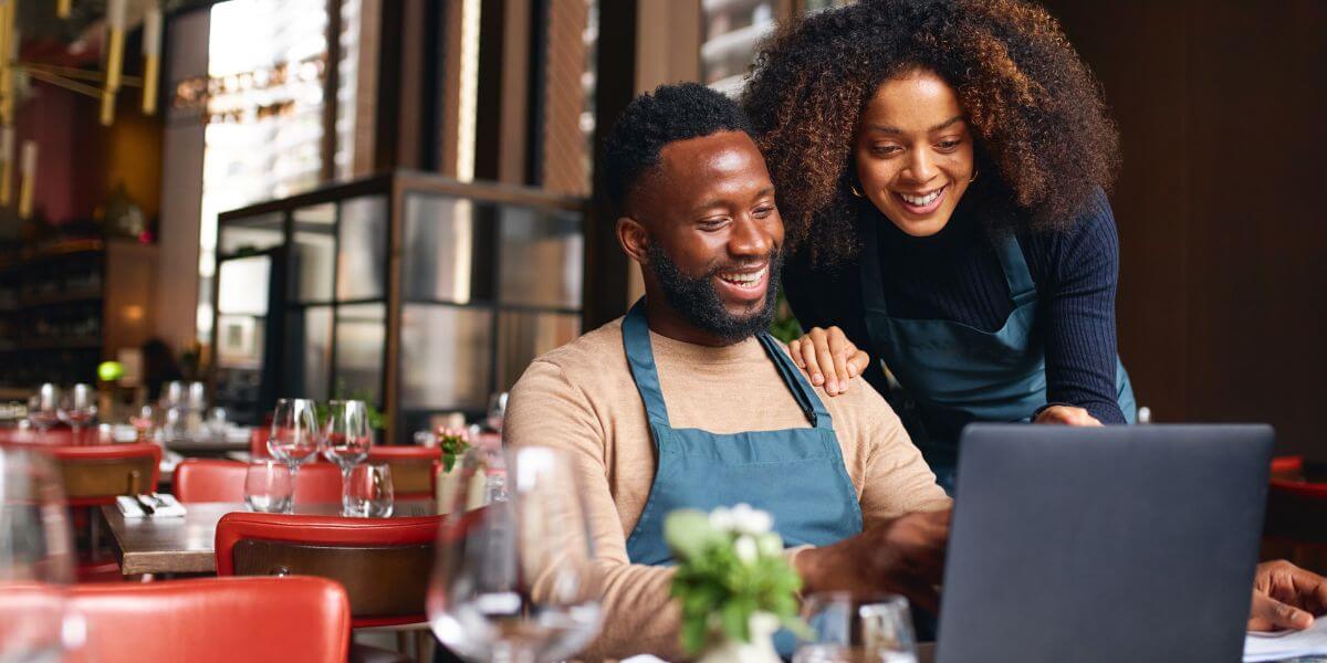 man and woman on laptop at restaurant