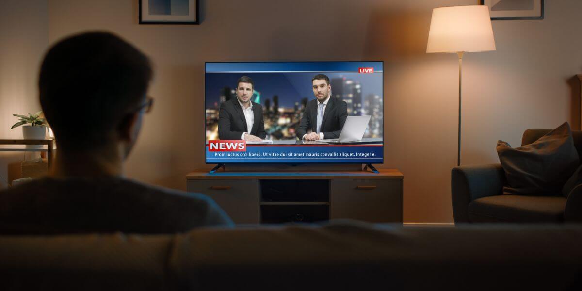 person watching news on couch