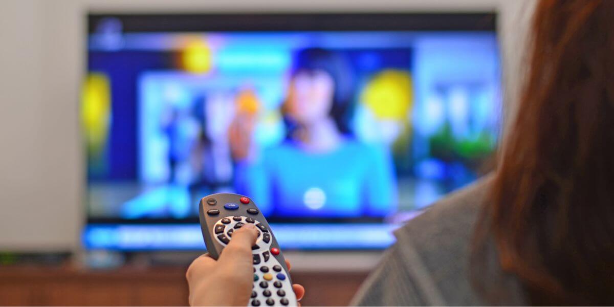 person watching news on couch with remote