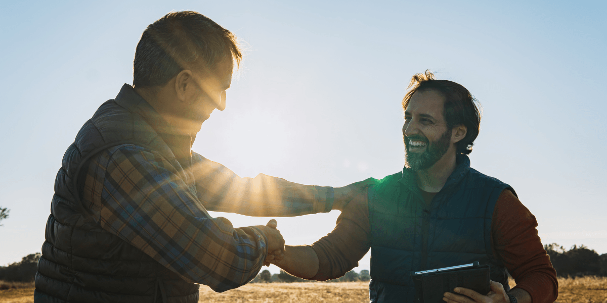 hombres dándose la mano en un campo