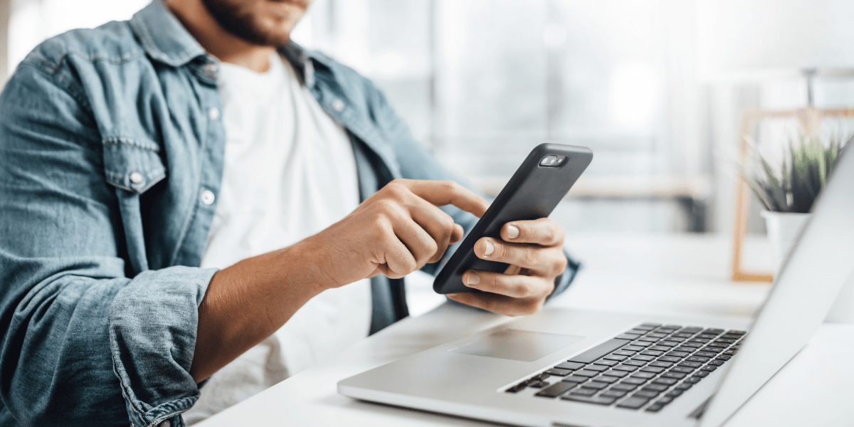 man looking at phone and laptop