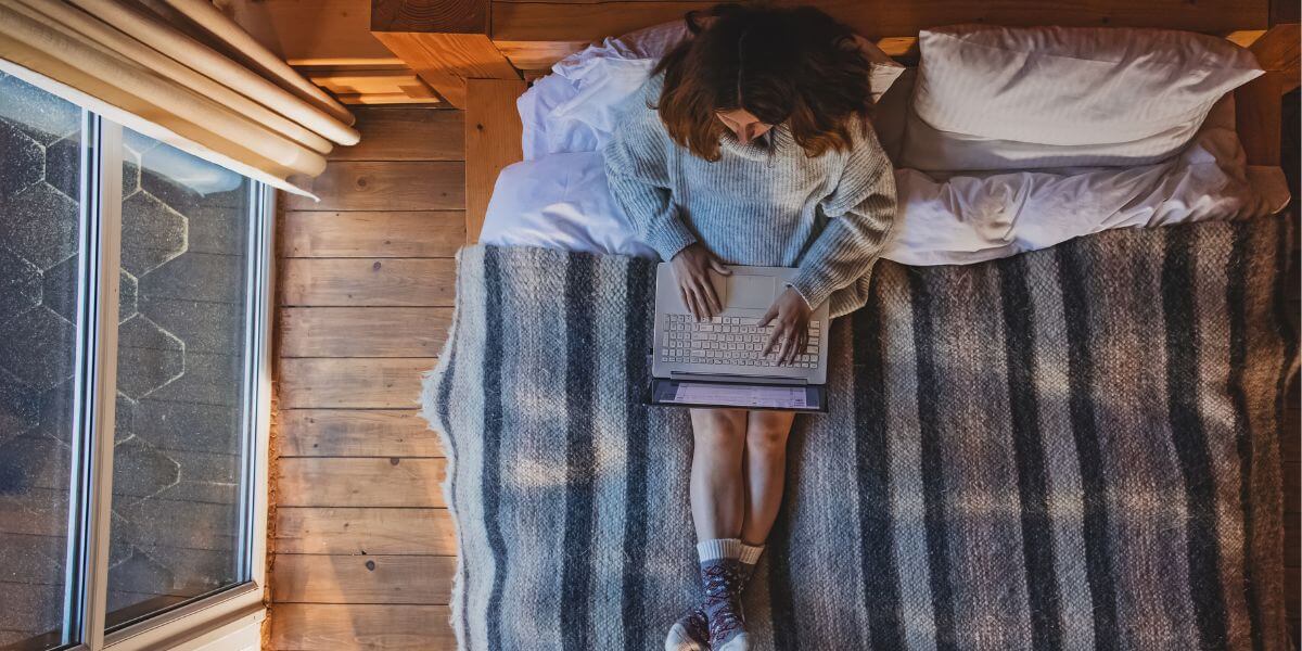 person using laptop on bed