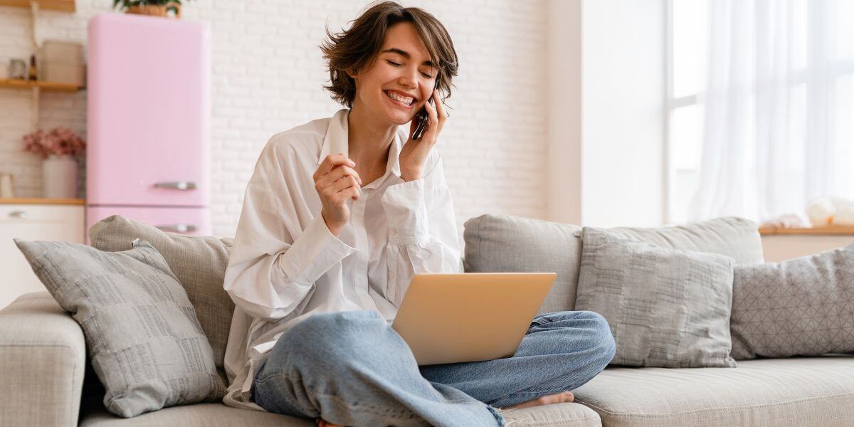woman on couch using phone and laptop