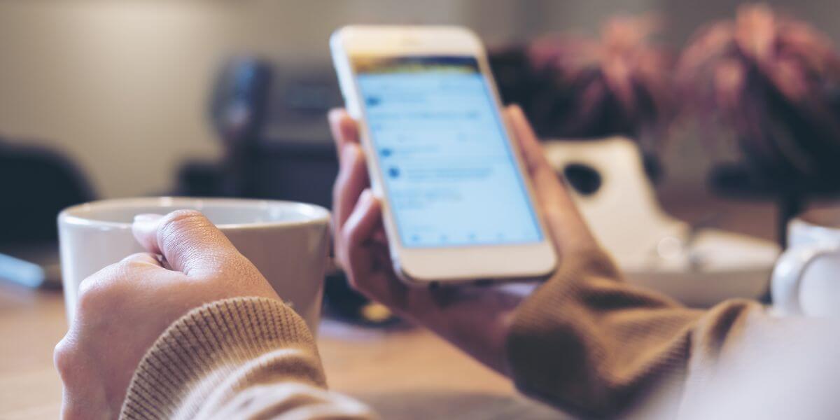 person drinking coffee and looking at phone