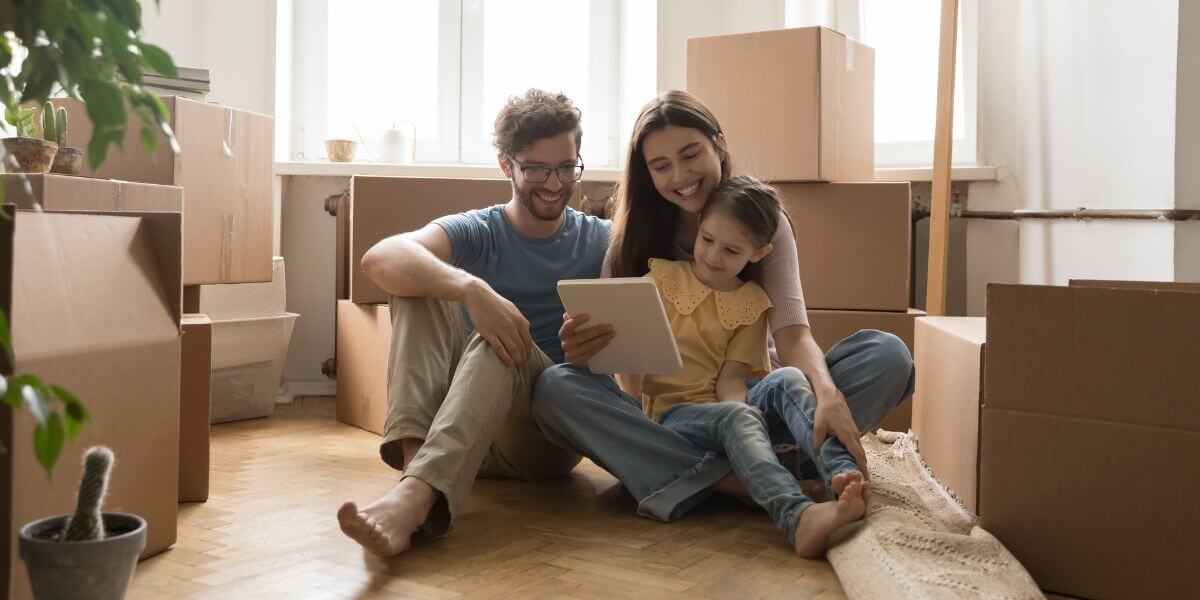 people sitting on floor with laptop and moving boxes