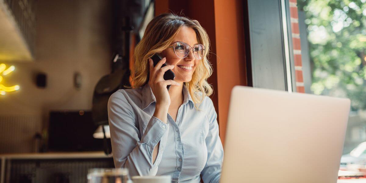 woman on phone using laptop