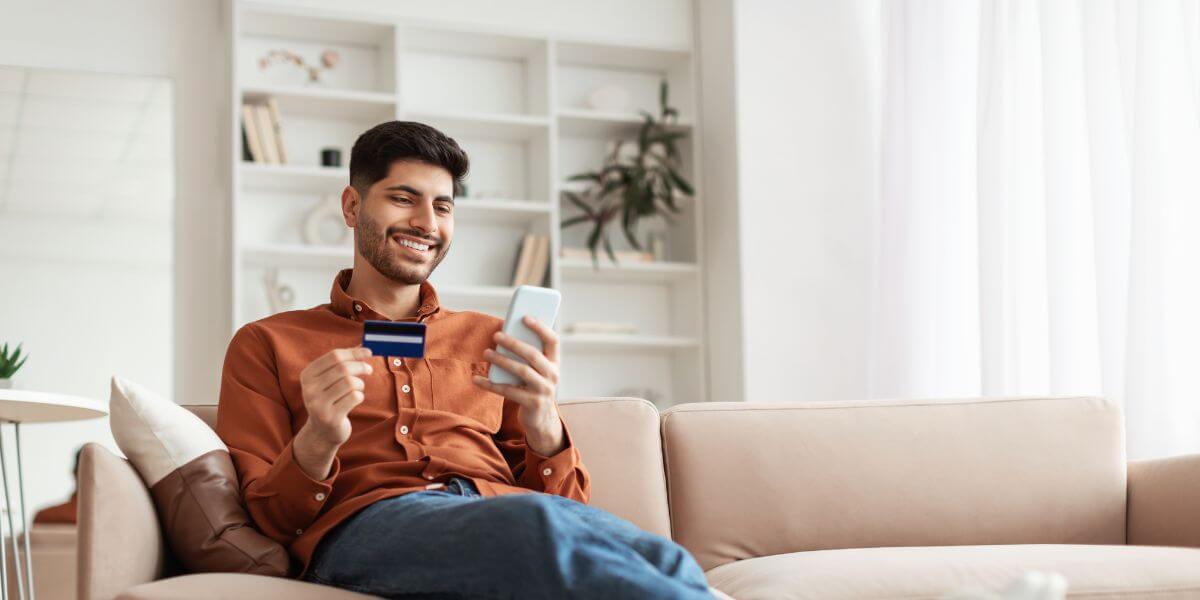 man looking at phone holding gift card