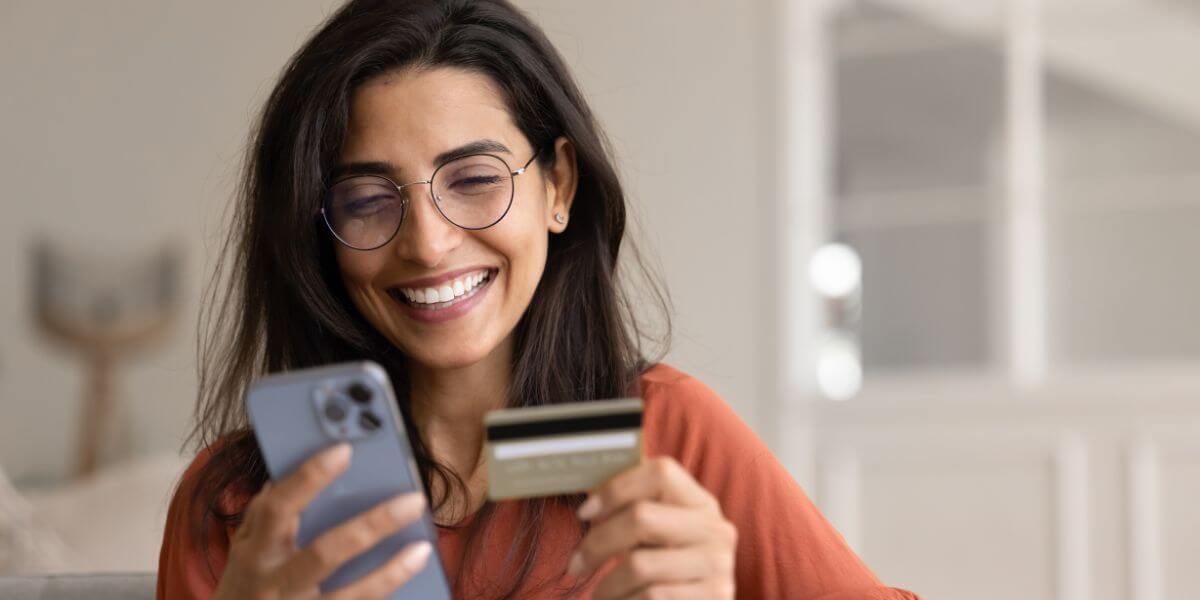 woman looking at phone holding gift card