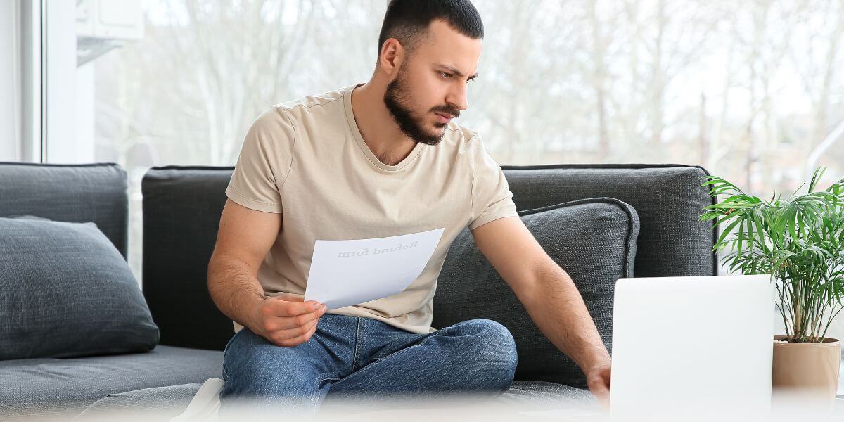 man holding paper using laptop