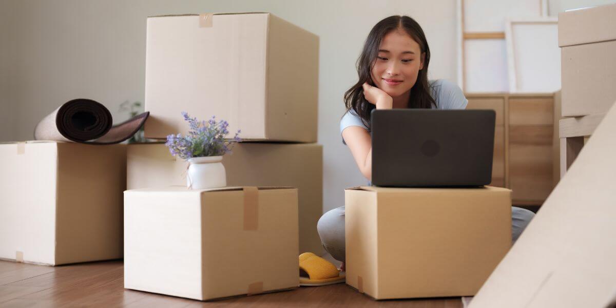 woman using laptop on boxes