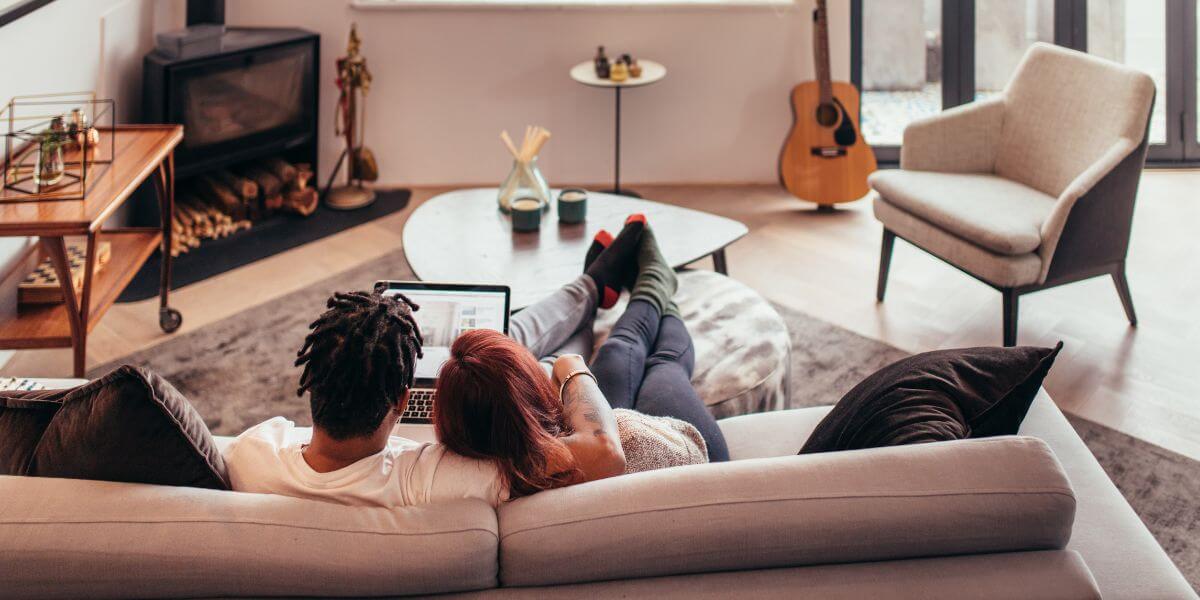 couple on couch in apartment with laptop
