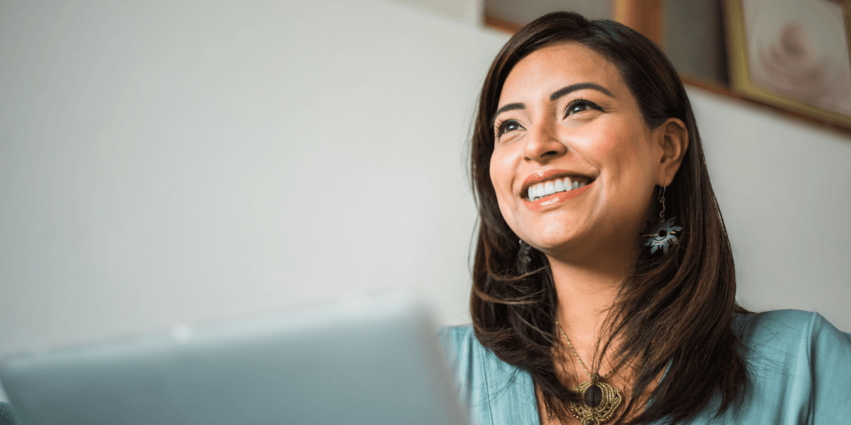 woman smiling while typing on laptop