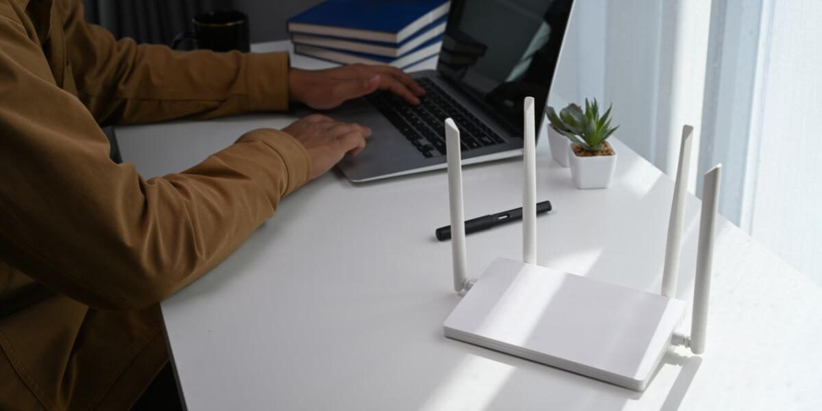 person at desk with laptop and router