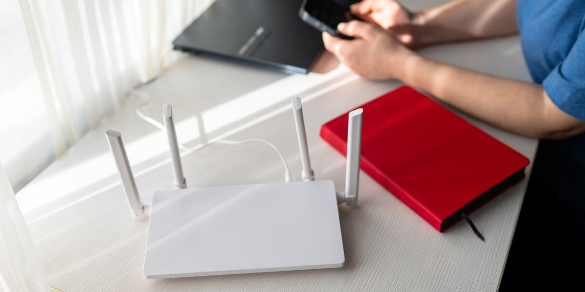 person at desk with laptop and router