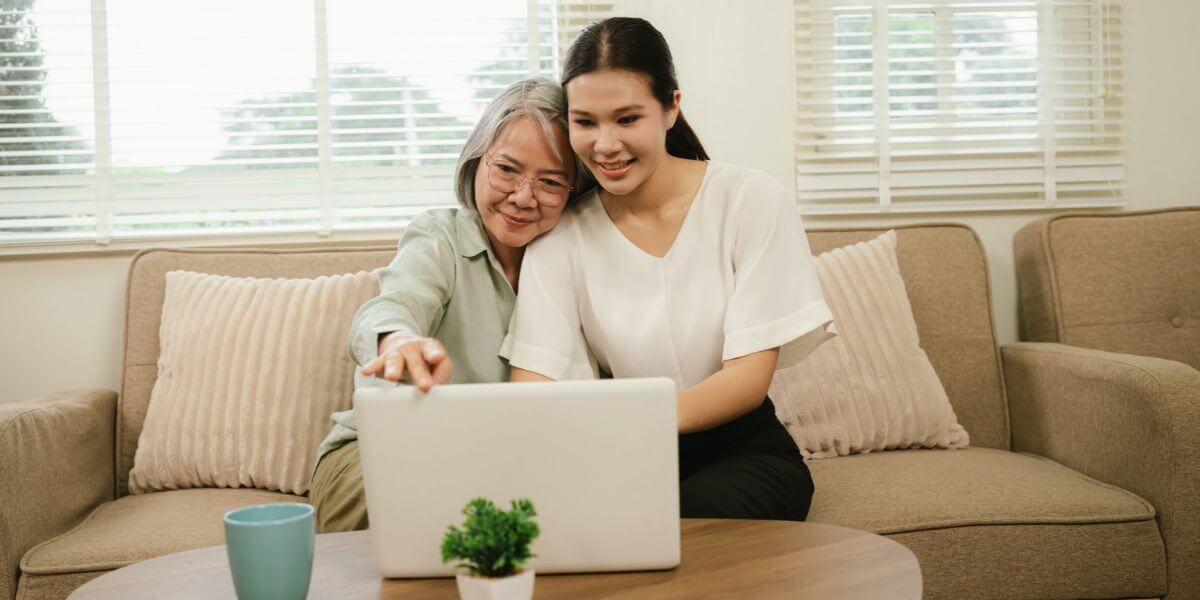 two women on couch using laptop