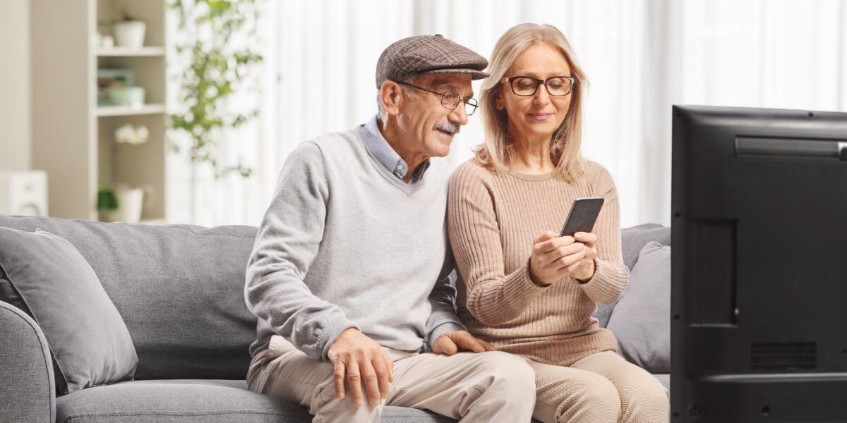 people with phone on couch watching TV