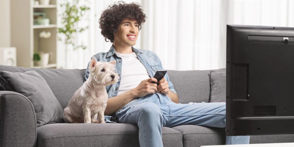 man with phone on couch watching TV