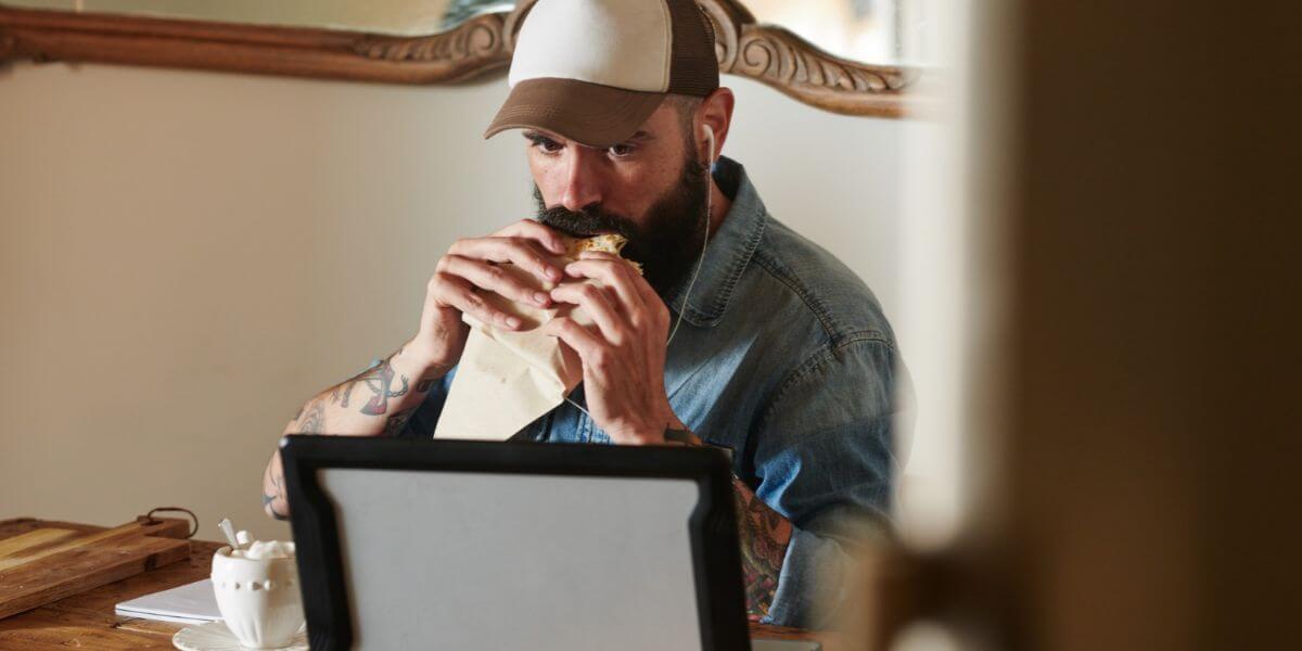 man watching laptop while eating